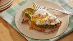 an egg and avocado toast on a plate with a fork next to it