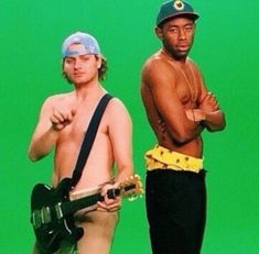 two shirtless men standing next to each other in front of a green screen holding guitars