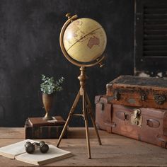 an old fashioned globe sitting on top of a tripod next to two suitcases