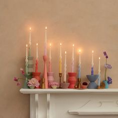 there are many different colored candles on the mantle