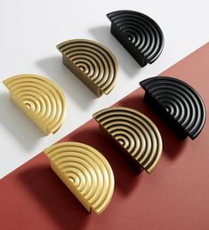 four black and gold plates sitting on top of a red and white table next to each other