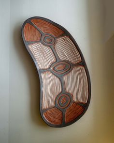 a brown and black plate hanging on the wall next to a white wall in a room