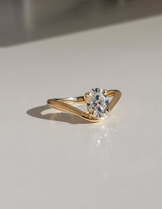 a yellow gold engagement ring with a single diamond in the center on a white surface