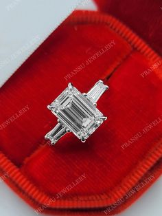 an emerald cut diamond ring in a red velvet case