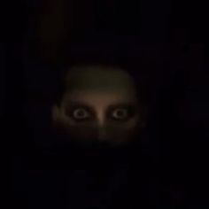 an evil looking man in the dark with his eyes wide open