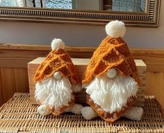 two crocheted gnomes sitting on top of a wooden box in front of a mirror