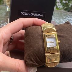 Dolce & Gabbana Gold Bracelet Watch I Accept Offers! Preloved But In Excellent Condition! Minor Scratches Shown Above Includes Box Gold Stainless Steel L: 7" X W: .75" White Dial Non-Numerical Hour Markers Box Clasp Fastening Water Resistant Rating 3 Atm Clasp Functions Perfectly Brand New Battery! I Ship Same Day! I Accept Offers! Check Out My Closet For Designer Items Of Every Shape & Size! Elegant White Watch With Bracelet Strap, Elegant White Watches With Bracelet Strap, Designer White Jewelry With Rectangular Dial, Box Clasp, Designer Items, Square Watch, White Dial, Accessories Watches, Bracelet Watch