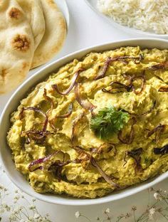 a white bowl filled with guacamole next to rice and pita bread