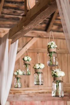 hanging mason jars filled with white flowers and greenery are the focal point for this rustic wedding