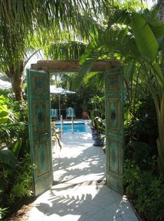 an open door leading to a pool surrounded by greenery