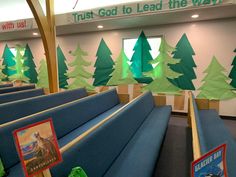 an empty church with blue benches and green trees on the wall in front of them