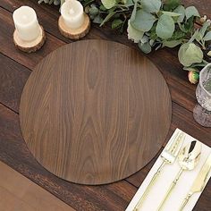 a place setting with candles, napkins and silverware on a wooden table top