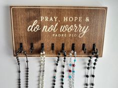 a wooden sign that says pray, hope and do not worry with beads hanging from it