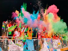 a group of people standing behind a fence covered in colored powder