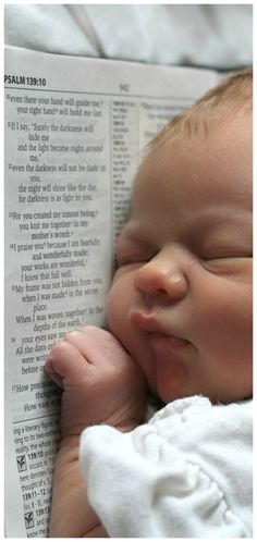 a baby sleeping on top of an open book with its head resting on it's hand