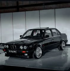 a black car parked in front of a white wall