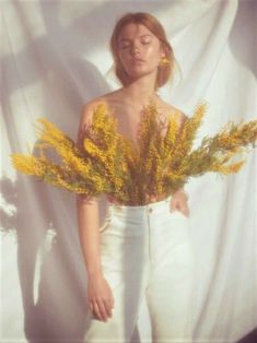 a woman with her eyes closed holding some yellow flowers