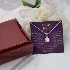 a purple card with a white rose next to it and a wooden box on the table