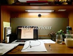 a laptop computer sitting on top of a wooden desk next to a cup and pen