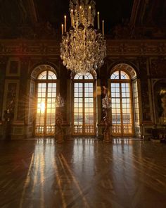 a chandelier hangs from the ceiling in an ornate room with large windows and marble floors