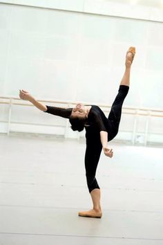 a woman is doing a handstand in a dance studio with her legs spread out