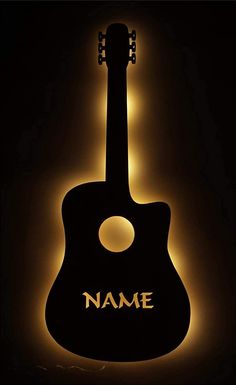 an acoustic guitar with the name on it is lit up against a dark background,