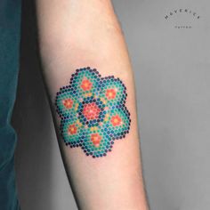 a colorful dot work tattoo on the left inner arm and forearm, with an orange flower in the center