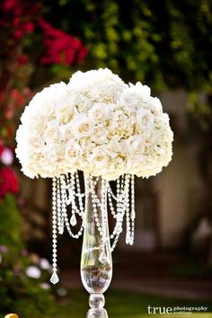 a vase filled with white flowers on top of a lush green plant covered in crystal beads