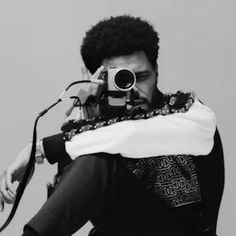 a man holding a camera up to his face while wearing a scarf around his neck