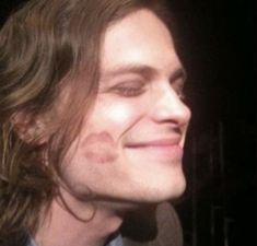 a close up of a person with long hair and a smile on his face in the dark