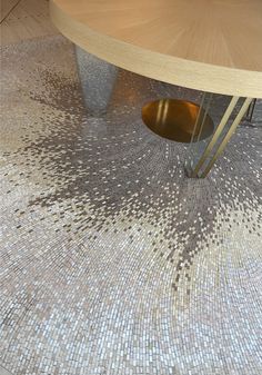 a wooden table sitting on top of a floor covered in small white and brown tiles