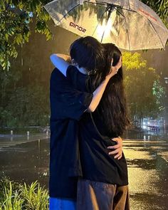 two people hugging under an umbrella in the rain