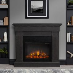 an electric fireplace in a living room with bookshelves and pictures on the wall