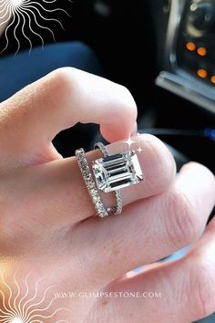 a woman's hand holding an engagement ring in the middle of her fingers,