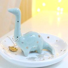 a small blue dinosaur figurine on a white plate with gold stars around it