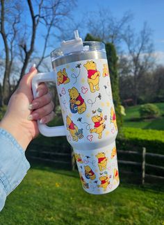 someone holding up a winnie the pooh travel mug