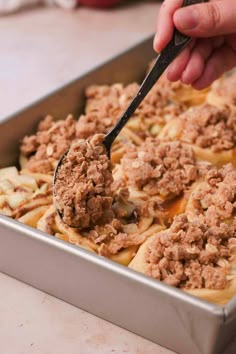 a person scooping some food out of a baking pan with a spoon in it