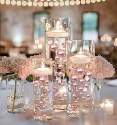 the centerpieces are filled with pink flowers and lit candles in glass vases