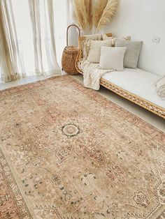 an antique rug is displayed in front of a couch with pillows and blankets on it