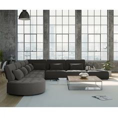 a living room with large windows and a sectional couch in the middle, along with a coffee table