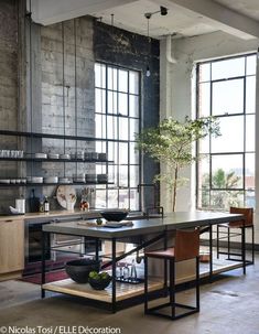 an industrial style kitchen with large windows and lots of counter space in the middle of the room