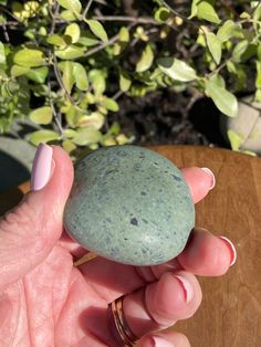 a person holding a green rock in their left hand with pink nail polish on it