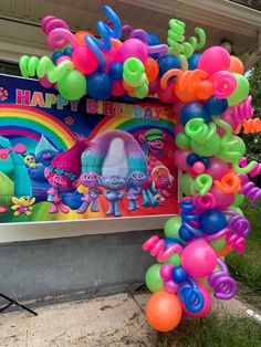 there is a birthday decoration with balloons and streamers in the shape of rainbows