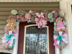 a decorated front door with wreaths and gingerbread cookies on the top, along with other decorations