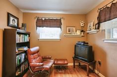 a living room with a chair, television and bookshelf on the far wall