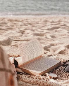 an open book sitting on top of a beach next to a pair of flip flops