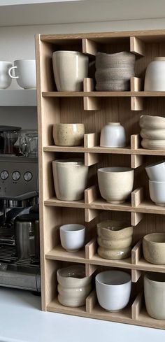 a shelf filled with lots of white dishes on top of a kitchen counter next to an oven