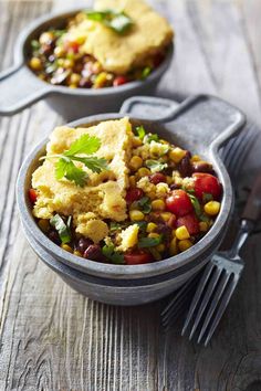 two bowls filled with food on top of a wooden table