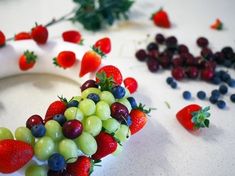 grapes, strawberries and other fruits are arranged in the shape of a wreath on a table