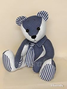 a blue and white teddy bear sitting on top of a table next to a wall